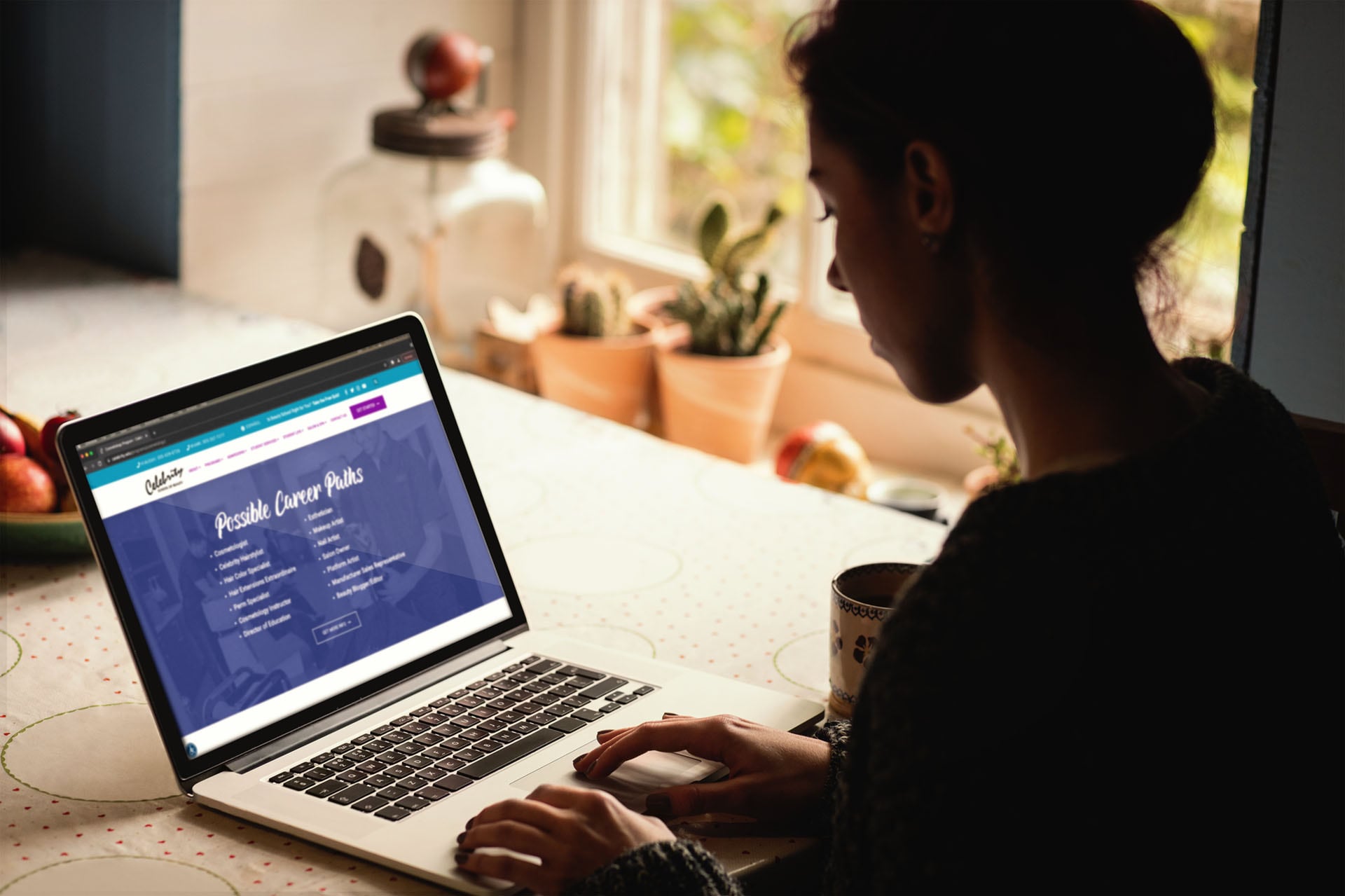 Celebrity School of Beauty website displayed on a laptop in a woman's kitchen.