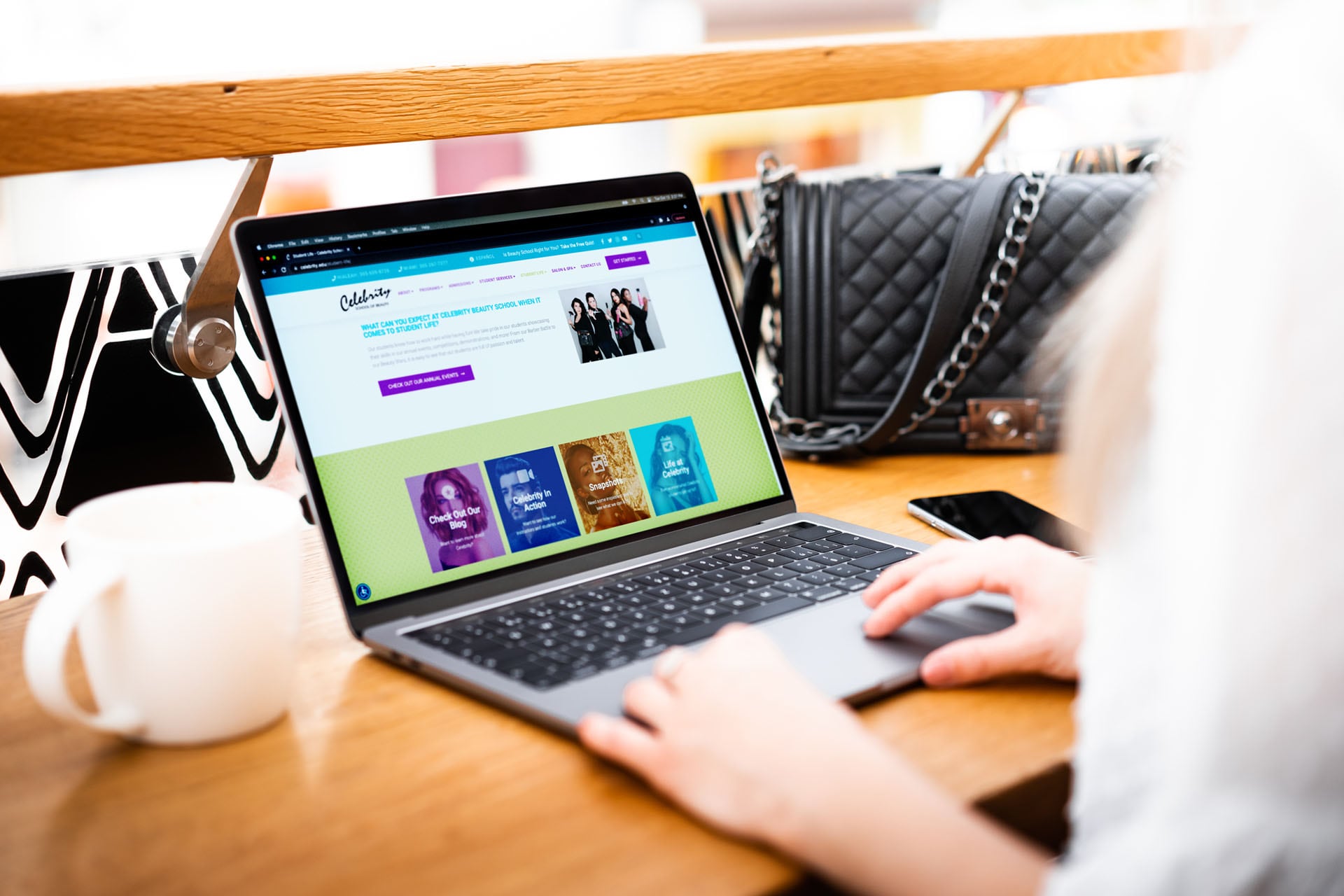 Celebrity School of Beauty website displayed on a laptop while a woman uses it.