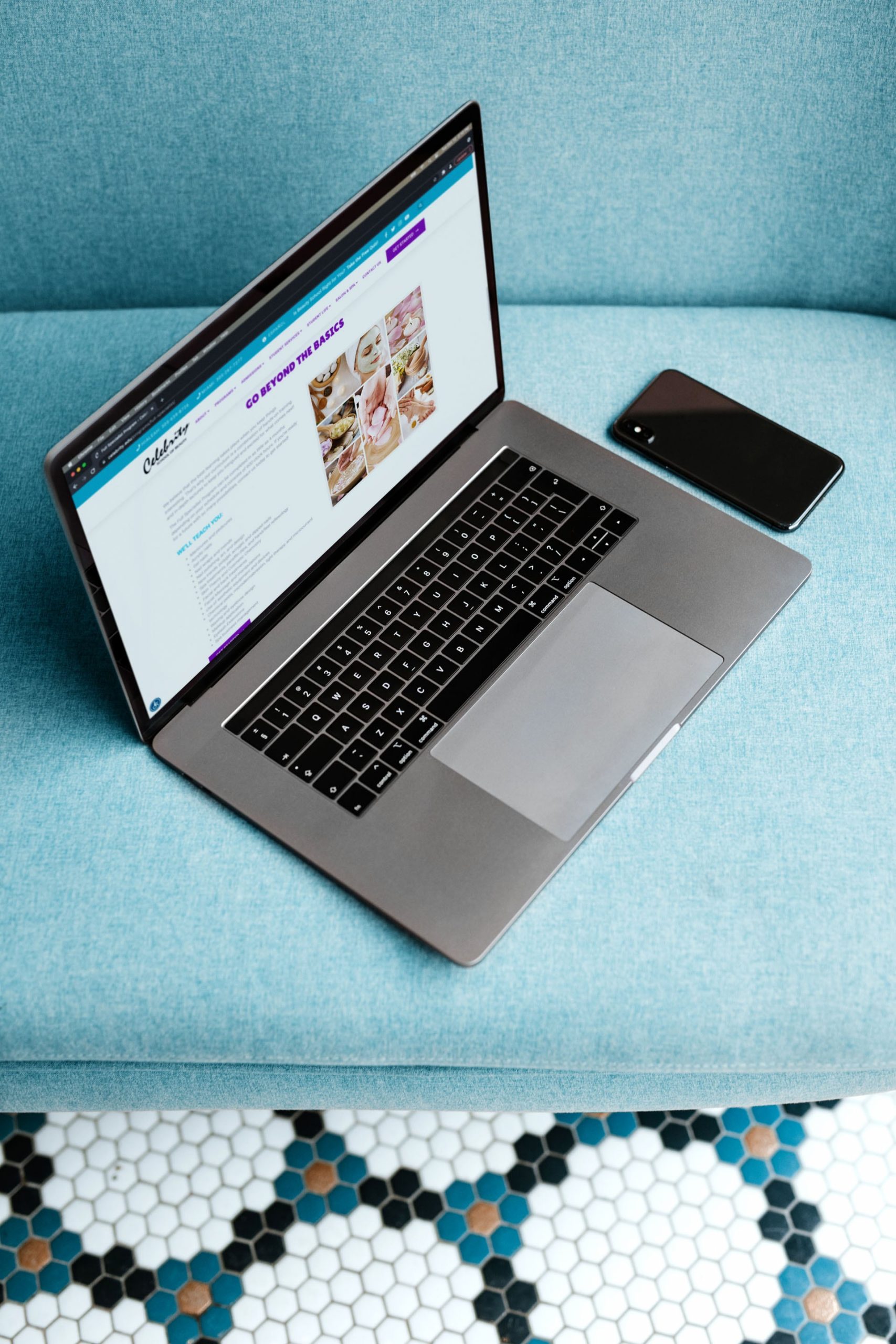 Celebrity School of Beauty website displayed on a laptop on a teal couch.
