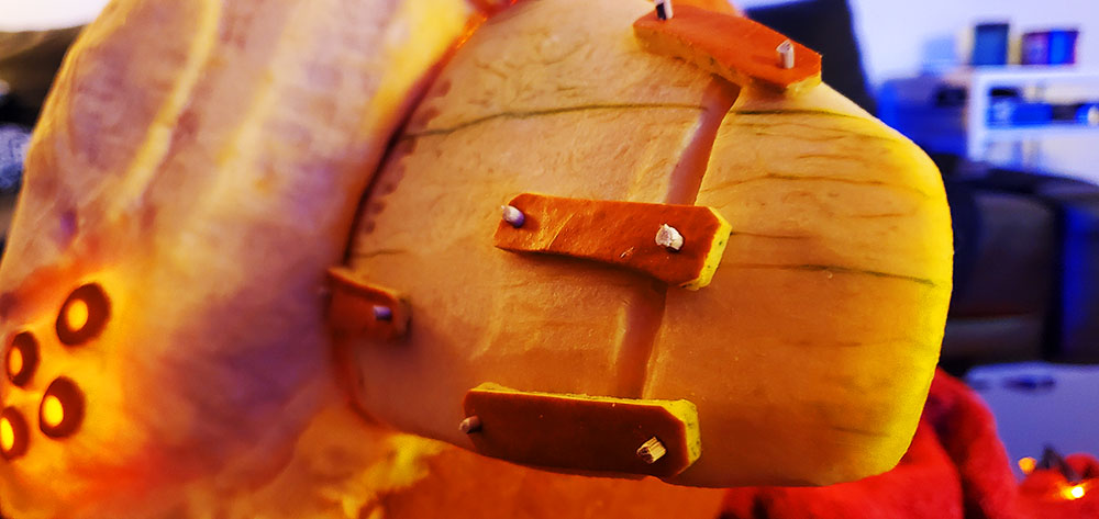 Close-up detail of the helmet fins of the Taniks, the Scarred pumpkin carving. Wooden dowels pin pieces of pumpkin exterior to the carved surface, mimicking the scrap metal appearance of the Fallen.
