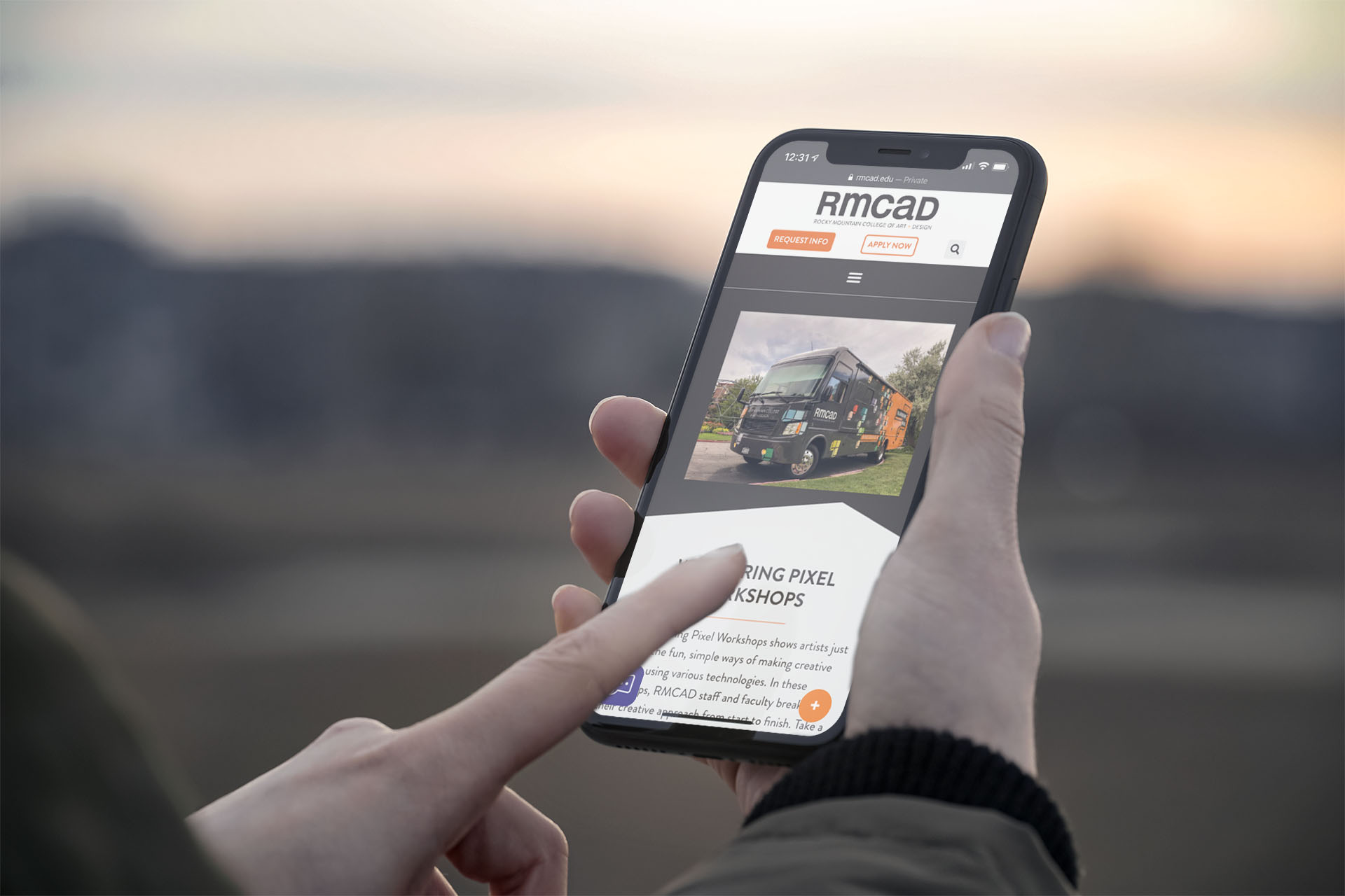 RMCAD website displayed on a mobile device as a user interacts with it outdoors, scrolling through the Wandering Pixel outreach page.
